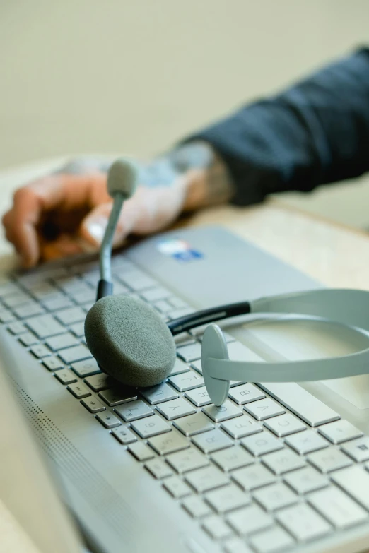 a close up of a person using a laptop with headphones on, by Jason Felix, art & language, holding a caduceus staff, in an call centre office, wearing bionic implants, grey