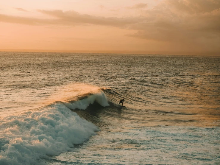 a man riding a wave on top of a surfboard, by Daniel Lieske, pexels contest winner, pastel orange sunset, big overcast, instagram post, reefs