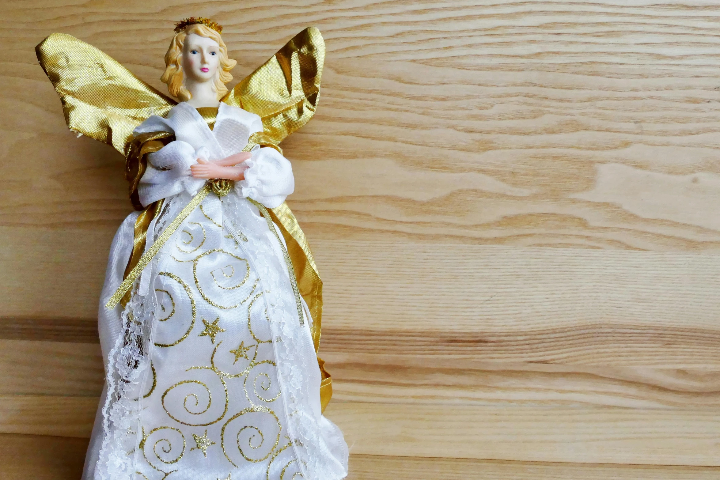 a close up of a figurine on a wooden surface, by Marie Angel, pexels, renaissance, wearing festive clothing, gold and white, gif, full figure