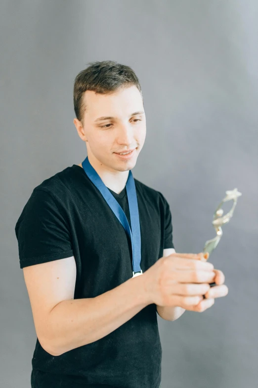 a man in a black shirt holding a flower, a colorized photo, by Adam Marczyński, pexels contest winner, twitch streamer / gamer ludwig, winning awards, russian academic, holding a wand