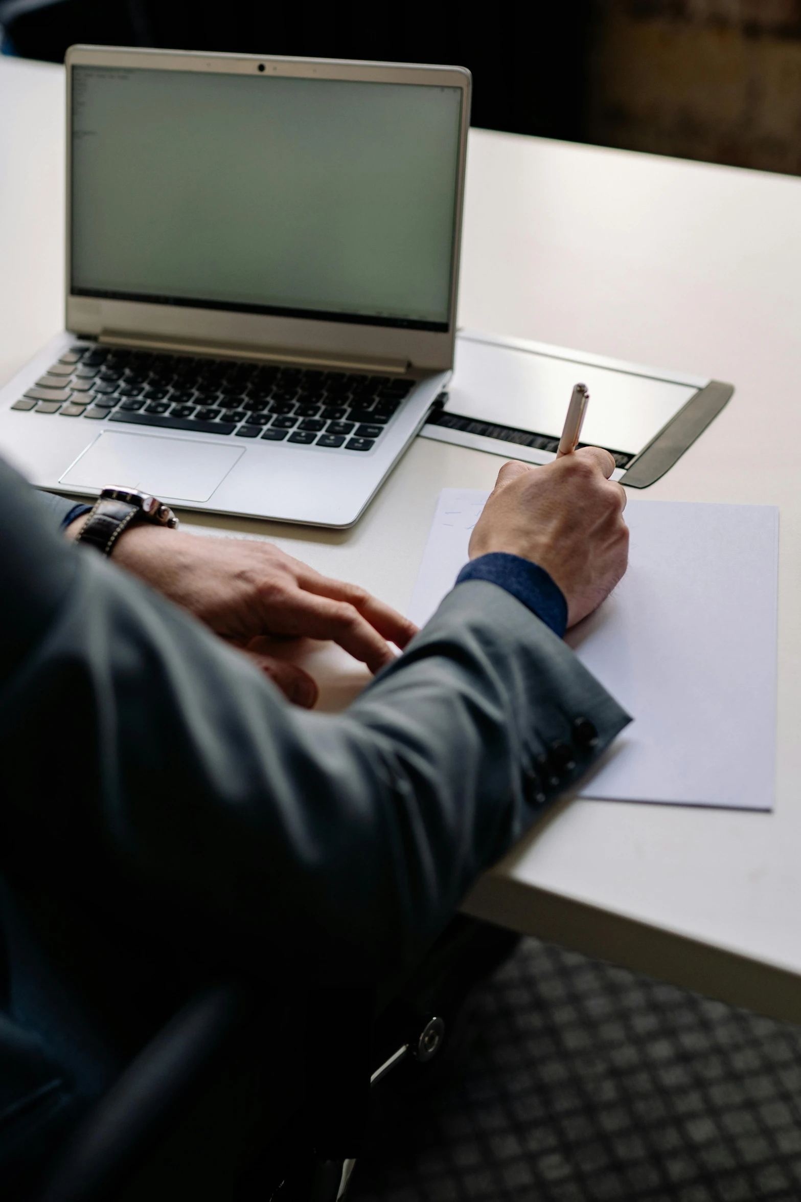 a man sitting at a desk in front of a laptop computer, by Carey Morris, pexels contest winner, pen on white paper, 🦑 design, lawyer, raphael personnaz