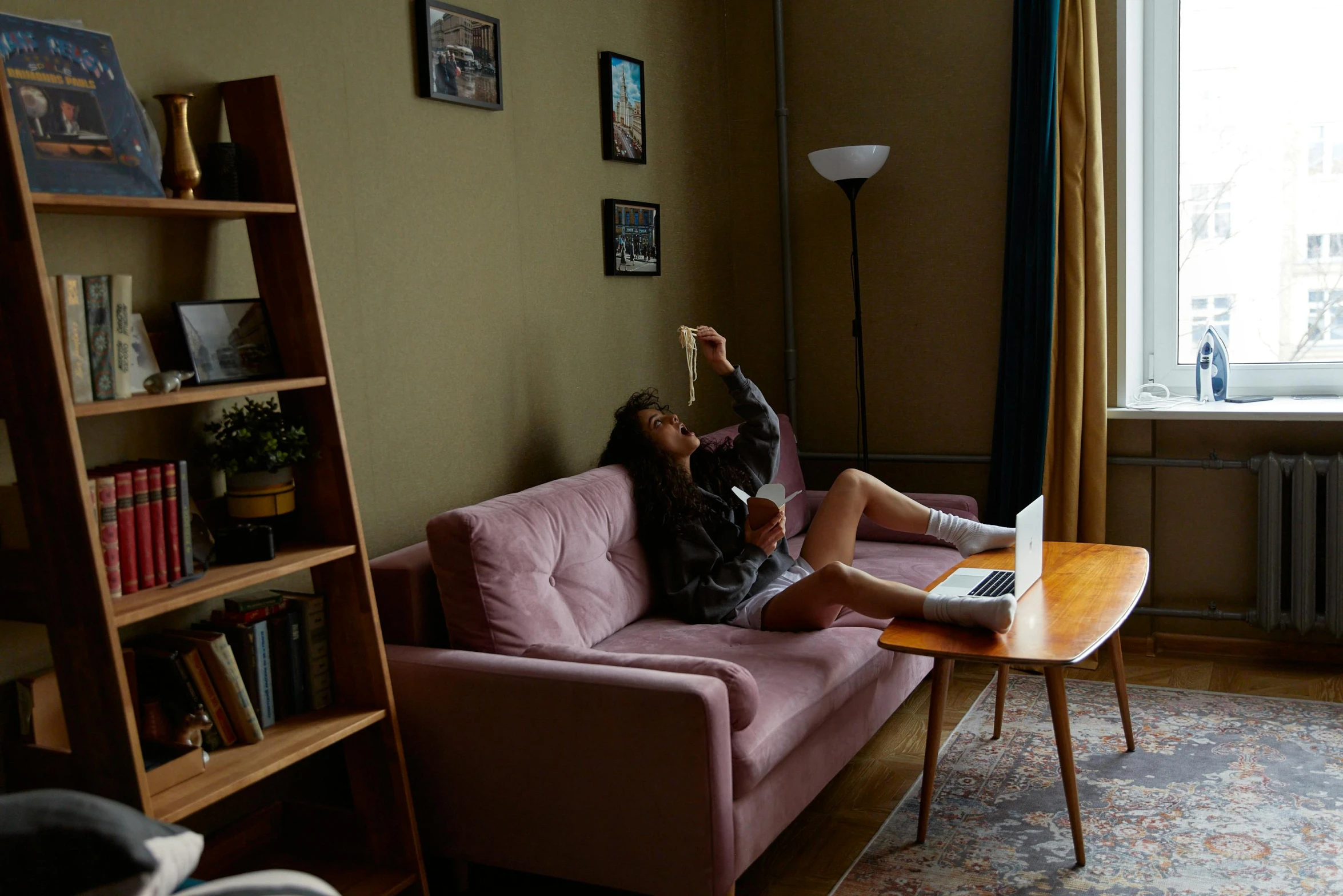 a woman sitting on a couch in a living room, inspired by Elsa Bleda, pexels contest winner, teenager hangout spot, couch desk, brown and pink color scheme, dramatic angle