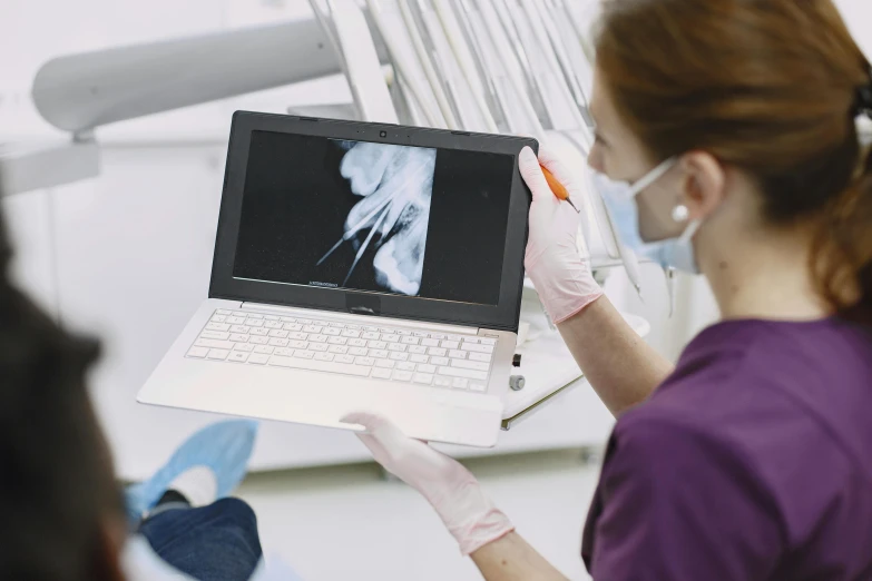 a woman in a dentist's chair holding a laptop computer, unsplash, exposed bone, xerography, instagram picture, darren bartley