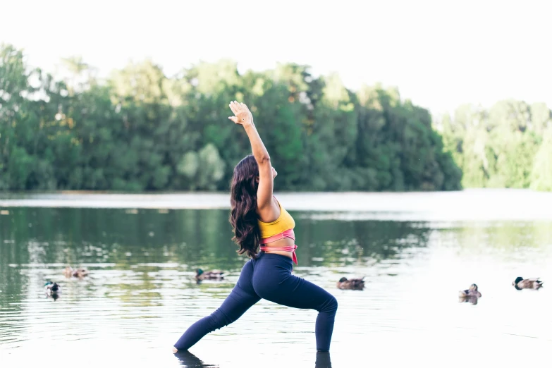 a woman doing yoga in front of a body of water, unsplash, arabesque, sydney park, shapely derriere, slightly blurred, various posed