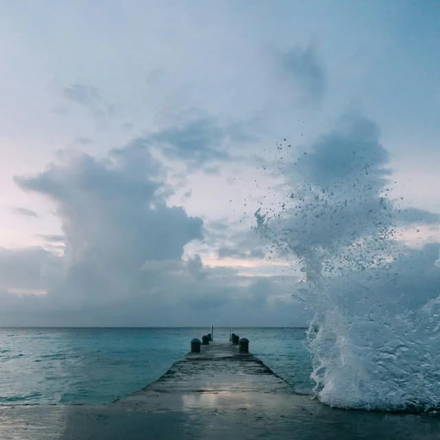 a wave crashes over a pier into the ocean, pexels contest winner, maldives in background, ocean spray, cloud vortex, drops around