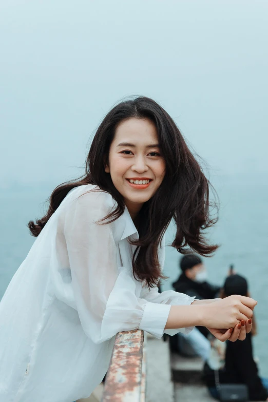 a woman standing on top of a pier next to the ocean, by Tan Ting-pho, happening, young adorable korean face, smiling slightly, wavy, avatar image