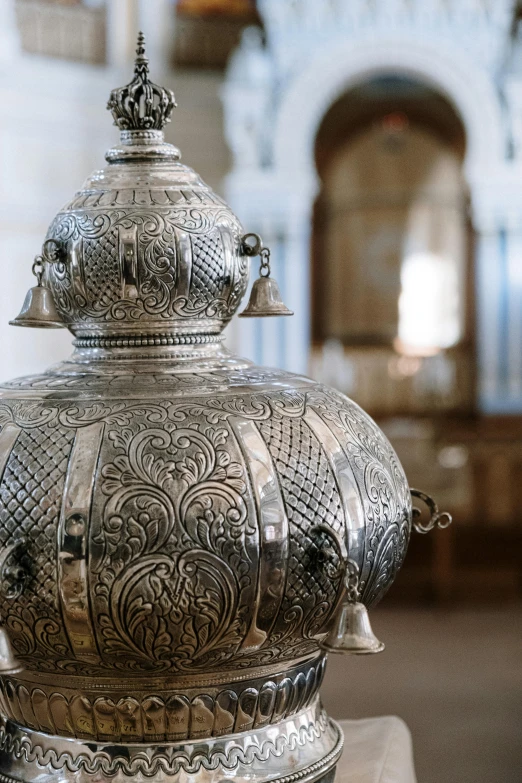 a silver vase sitting on top of a wooden table, with great domes and arches, symmetrical and intricate, orthodox, in detail