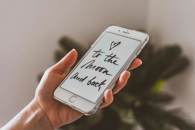 a person holding a cell phone with writing on it, by Julia Pishtar, trending on pexels, to the moon, white backround, iphone wallpaper, positive mood