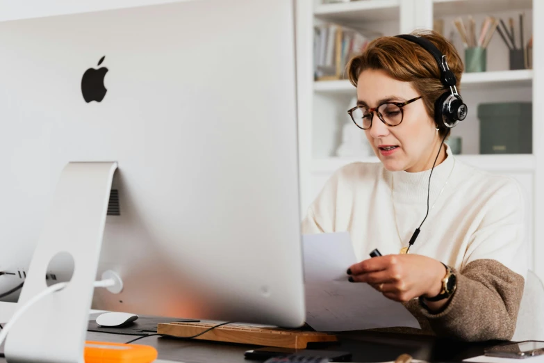 a woman sitting at a desk in front of a computer, by Julia Pishtar, trending on pexels, with head phones, nerdy music teacher with phd, link from zelda using computer, document photo