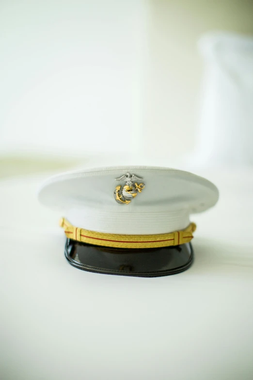 a white hat sitting on top of a white bed, by Mike Bierek, marine armor, post graduate, visor, the president