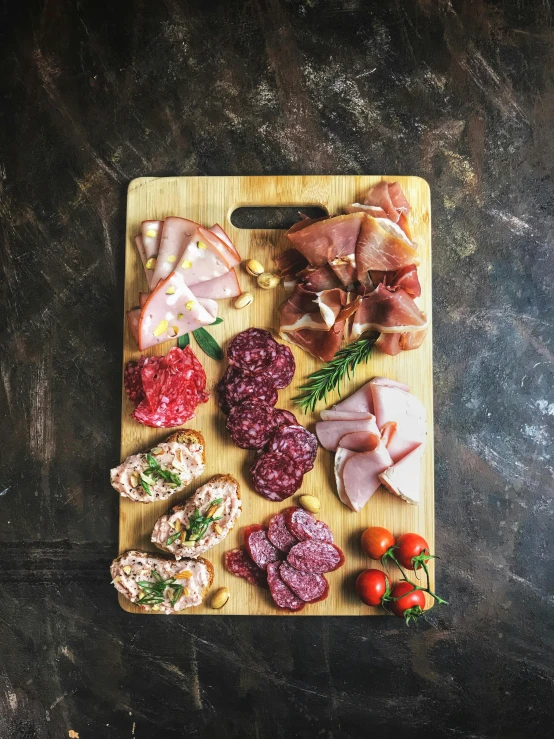 a wooden cutting board topped with meat and veggies, a picture, pexels, salami, high quality photo, a high angle shot, posing