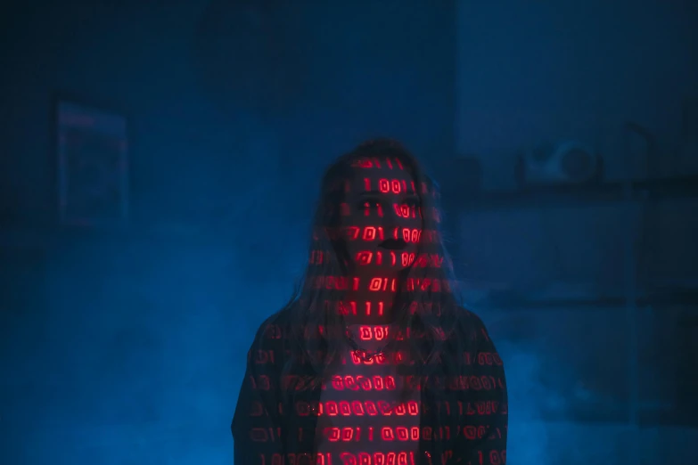 a person standing in front of a computer screen, a hologram, by Adam Marczyński, pexels, ascii art, bright red cape on her back, evil artificial intelligence, teenage girl, binary