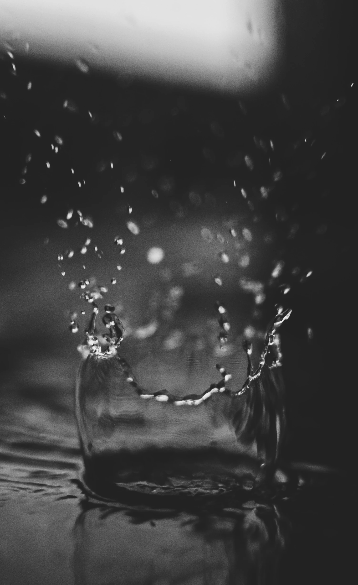 a glass filled with water sitting on top of a table, a black and white photo, pexels, conceptual art, falling rain, ffffound, late evening, draped with water and spines