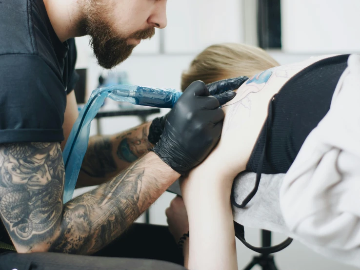 a man getting a tattoo on a woman's arm, a tattoo, by Adam Marczyński, trending on pexels, blue veins, black ink outline, half body photo, 2717433015