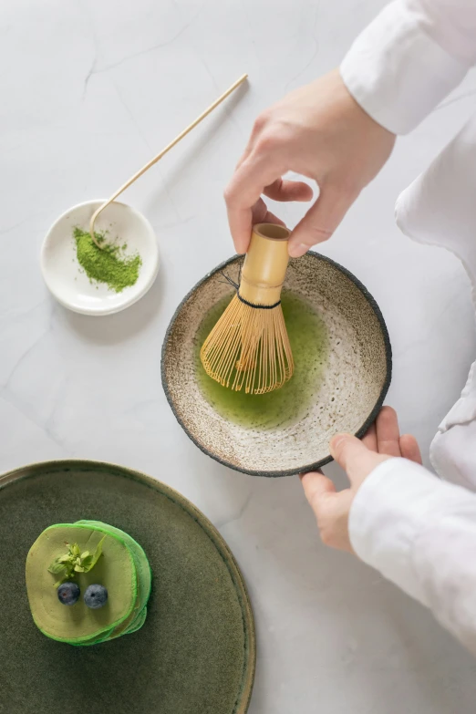 a person that is holding a whisk in a bowl, a picture, loputyn and matcha, plating, broad brush, displayed