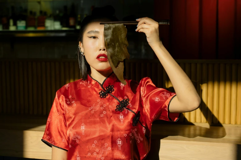 a woman in a red dress holding a mirror over her head, a portrait, inspired by Wen Jia, trending on pexels, chopsticks, wearing festive clothing, outlive streetwear collection, red lipstick on face
