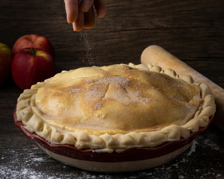 a person sprinkling sugar on a pie, pexels contest winner, apple, vibrating, various sizes, wooden bowl