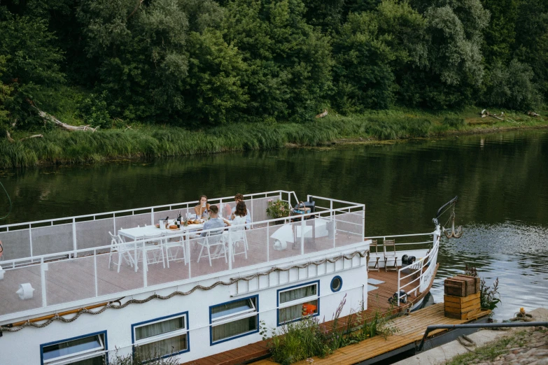 a boat sitting on top of a river next to a forest, un restaurant avec une terrasse, bartlomiej gawel, wedding, the deck of many things