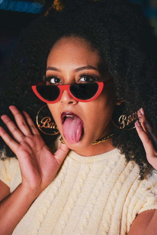 a woman sticking her tongue out while wearing sunglasses, an album cover, trending on pexels, bladee from drain gang, curls and curves, snacks, teenage vanessa morgan