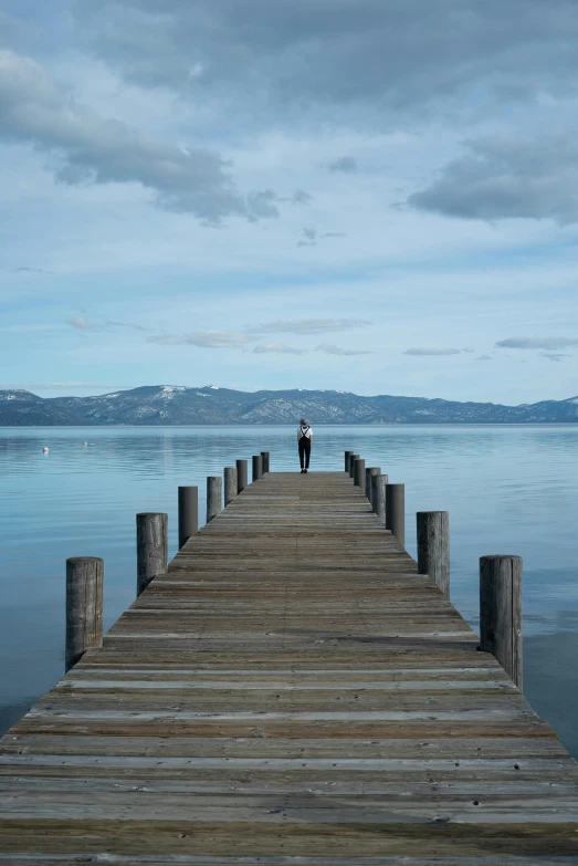 a person standing on the end of a pier, by Robbie Trevino, renaissance, idaho, calm seas, 8 k -, pareidolia