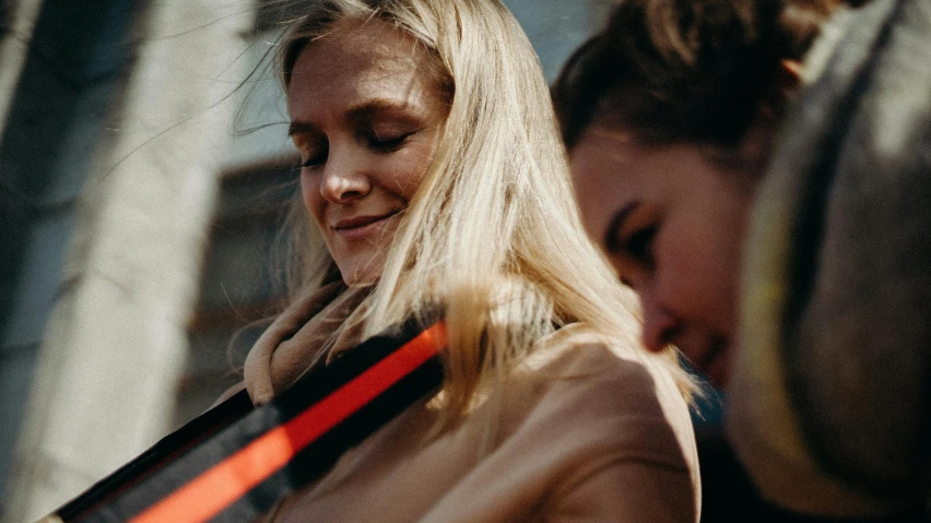 a couple of women standing next to each other, a photo, by Emma Andijewska, trending on pexels, happening, close up of a blonde woman, supportive, promotional image, low quality footage