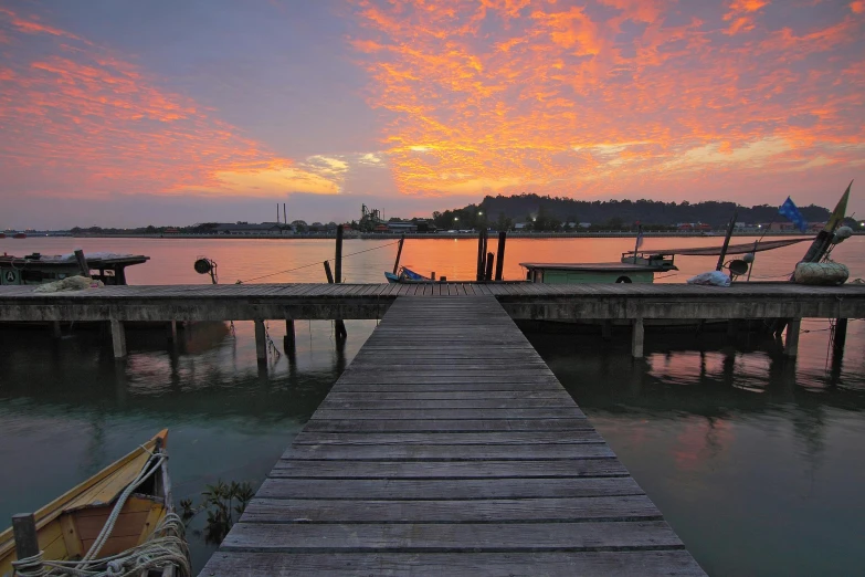 a dock next to a body of water at sunset, hurufiyya, abel tasman, orange / pink sky, family friendly, fishing village