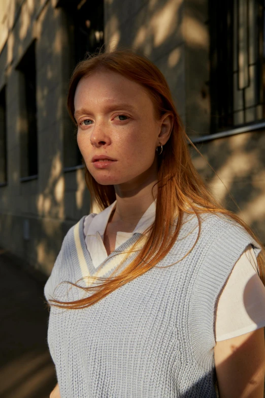 a woman standing on a sidewalk in front of a building, inspired by Louisa Matthíasdóttir, renaissance, wearing white v - neck top, wearing a light blue shirt, sleeveless turtleneck, close-up shoot