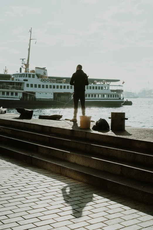 a man standing next to a body of water with a boat in the background, by Niko Henrichon, pexels contest winner, happening, fallout style istanbul, looking at spaceships at dock, full body profile, busy but lonely