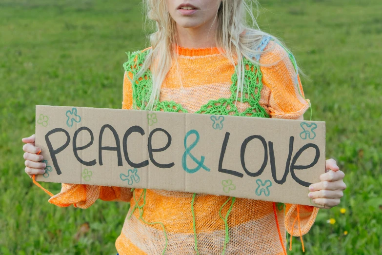 a little girl holding a sign that says peace and love, an album cover, close up of a blonde woman, orange and green power, cottagecore hippie, psytrance
