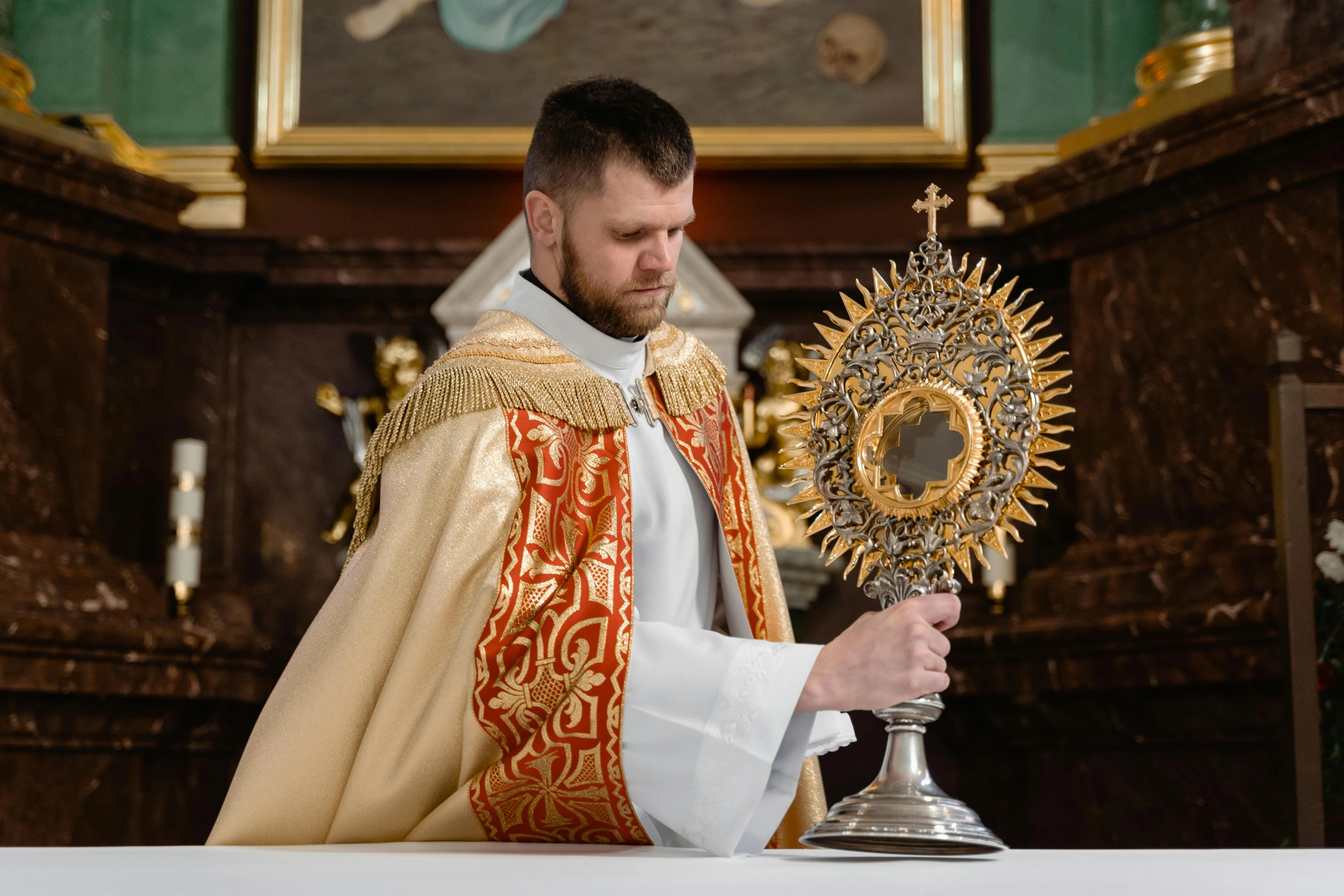 a man in a priest's robes holding a cross, a portrait, pexels contest winner, baroque, intricate ornament halo, solis sacerdotibus, he is about 20 years old | short, overturned chalice