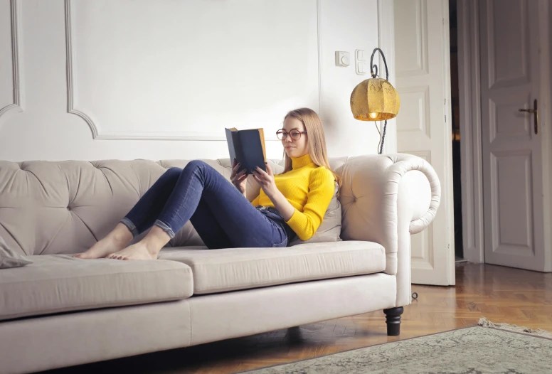 a woman sitting on a couch reading a book, inspired by Sarah Lucas, pexels contest winner, hansa yellow, emerging from her lamp, reading engineering book, teenage girl