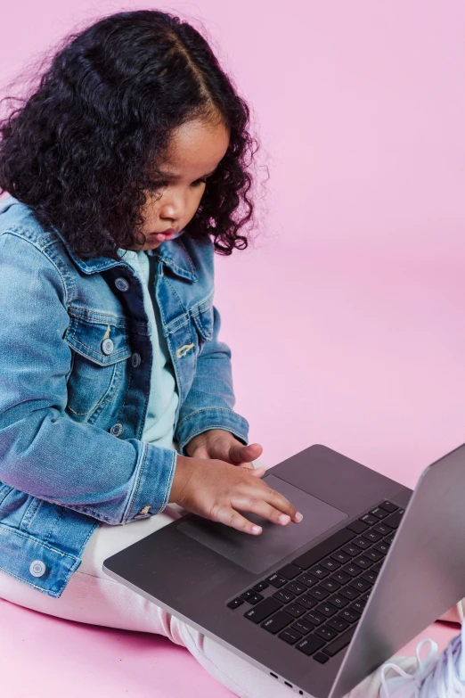 a little girl sitting on the floor with a laptop, pexels, solid background, computer science, official screenshot, an olive skinned