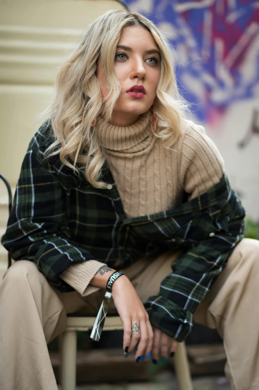 a woman sitting on top of a wooden chair, a portrait, trending on pexels, hurufiyya, tartan hoodie, cropped shirt with jacket, dasha taran, wearing casual sweater