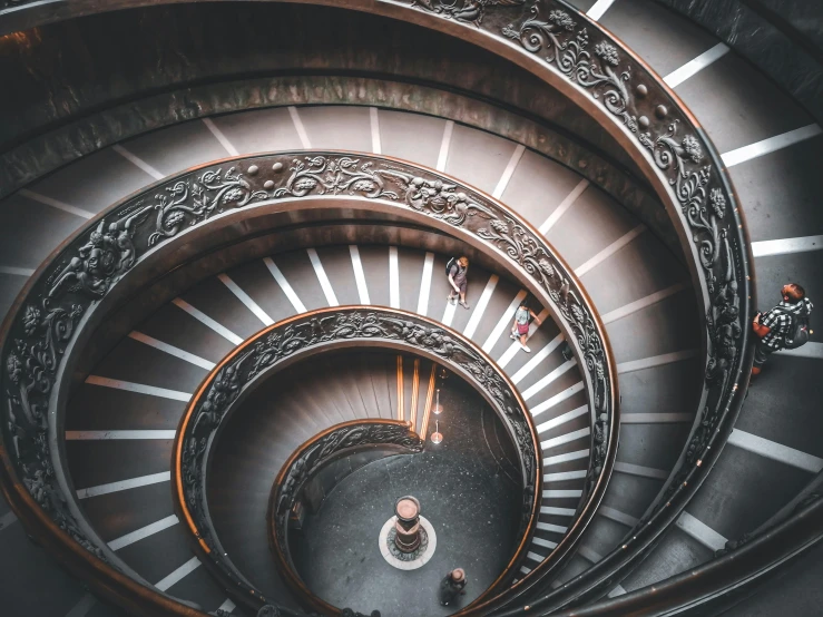 a spiral staircase with people walking down it, pexels contest winner, neoclassicism, brown, all roads lead to rome, 🦩🪐🐞👩🏻🦳, australian tonalism escher