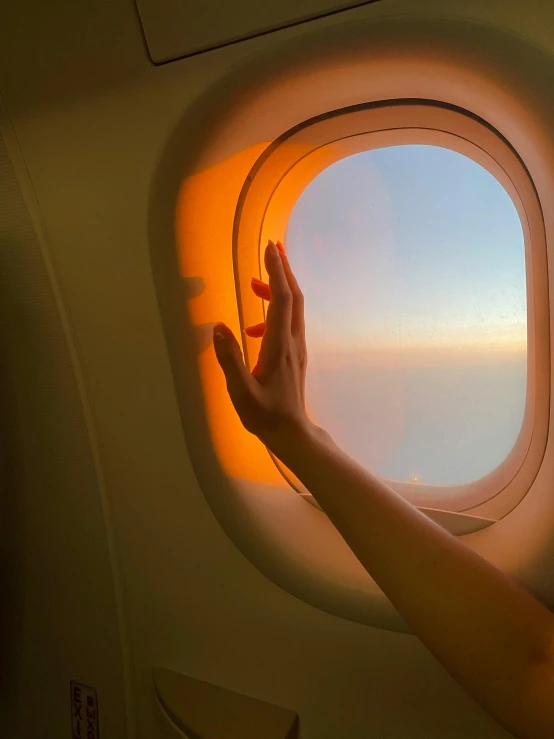 a person reaching out of an airplane window, orange skies, soft glowing windows, glowing aesthetic, waving arms