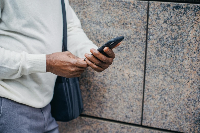 a close up of a person holding a cell phone, by Carey Morris, black man, casually dressed, background image, extra high resolution