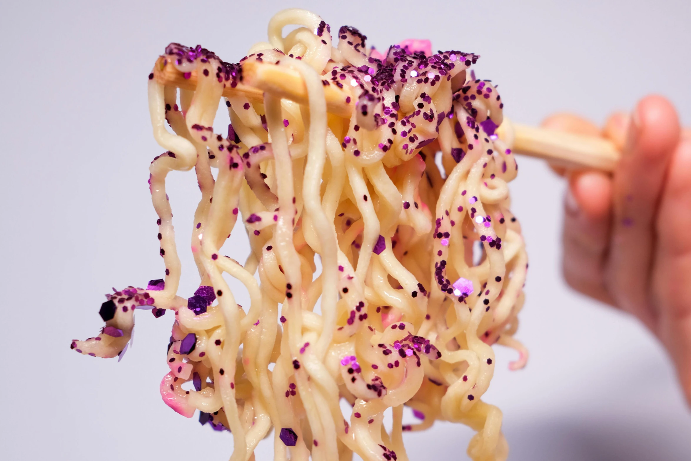 a person holding a pair of chopsticks over a bowl of noodles, an album cover, inspired by Shōzō Shimamoto, unsplash, white and purple, luscious with sesame seeds, closeup - view, twisted tentacles