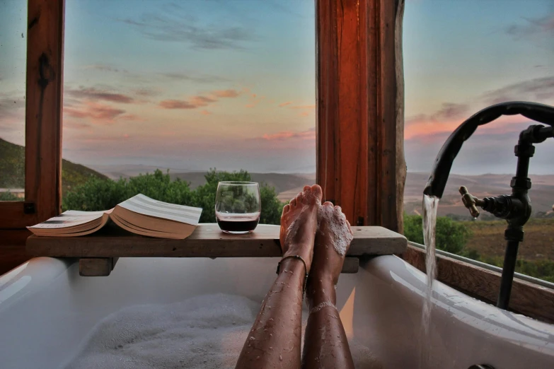 a person laying in a bath tub next to a window, hollister ranch, sunset view, instagram picture, bubbly