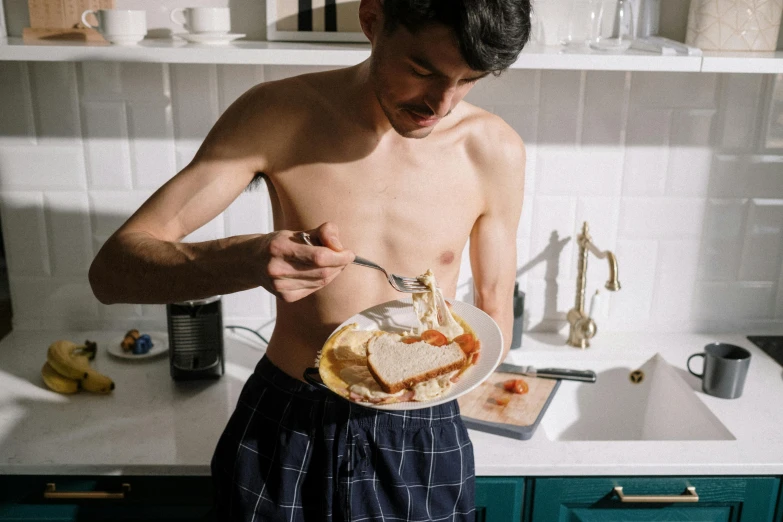 a man standing in a kitchen holding a plate of food, by Julia Pishtar, pexels contest winner, hyperrealism, bare chest, there is full bedpan next to him, eating cheese, physical : tinyest midriff ever