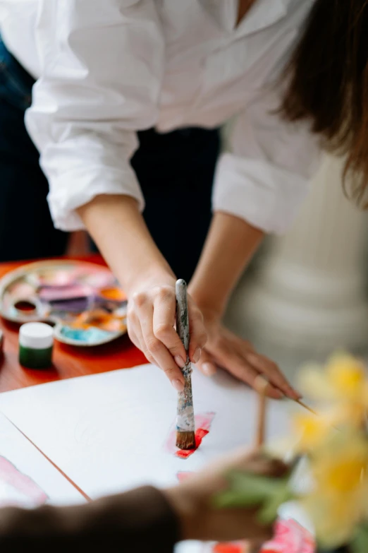 a woman is painting a picture on a piece of paper, trending on pexels, arbeitsrat für kunst, gourmet and crafts, red paint, oil inks, decorative art