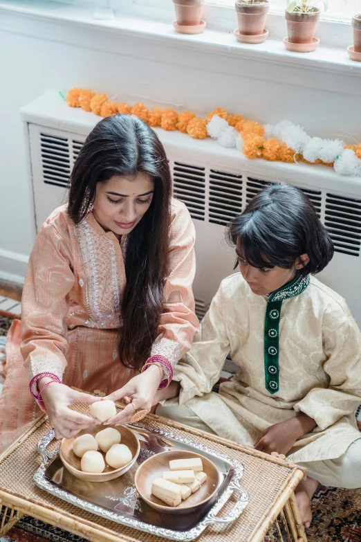 a woman and a child are sitting on the floor, by Riza Abbasi, reddit, wearing a silk kurta, holding easter eggs, candle lighting, profile image