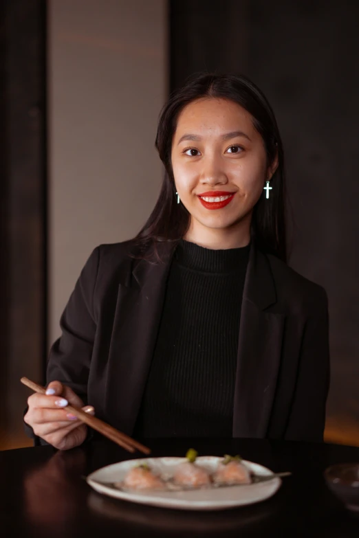 a woman sitting at a table with a plate of food, playing drums, feng zhu |, headshot profile picture, standing with a black background