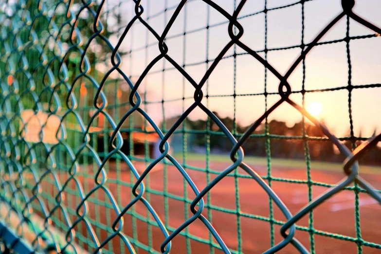 a view of a baseball field through a chain link fence, a digital rendering, by Niko Henrichon, pexels, square, setting sun, a green, islamic