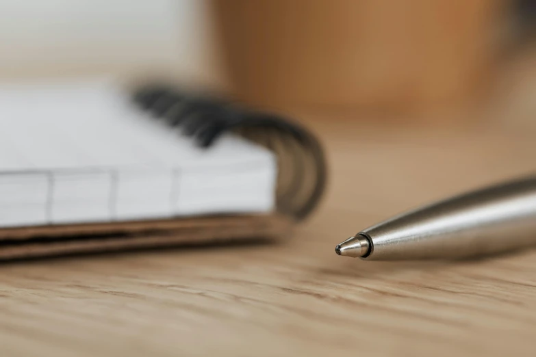 a pen sitting on top of a wooden table next to a notebook, trending on pexels, background image, multiple stories, thumbnail, brown