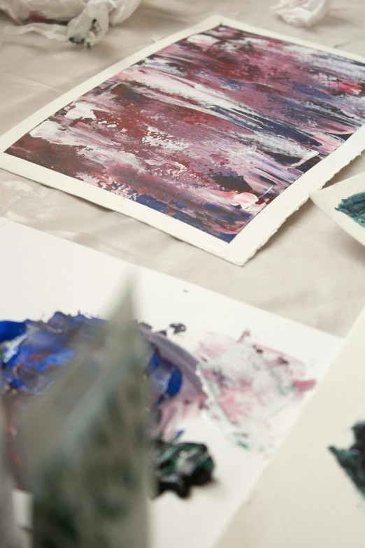 a group of paintings sitting on top of a table, inspired by Sam Francis, unsplash, close-up photograph, purple and blue colour palette, printed on paper, high quality image