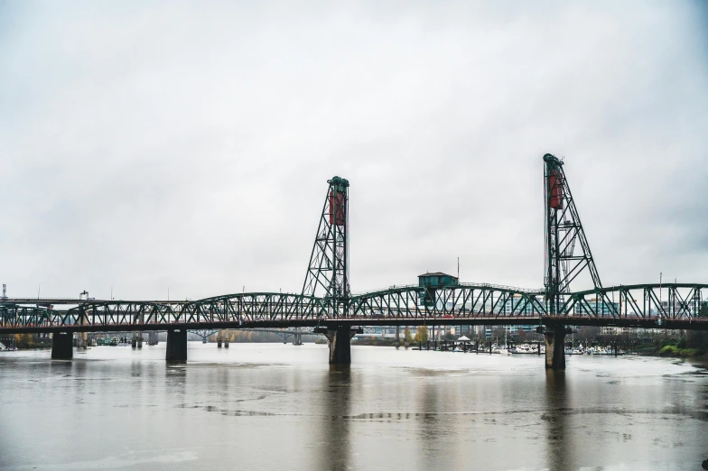 a bridge over a body of water under a cloudy sky, by Jacob Burck, pexels contest winner, portland oregon, frozen river, tall metal towers, full color photograph