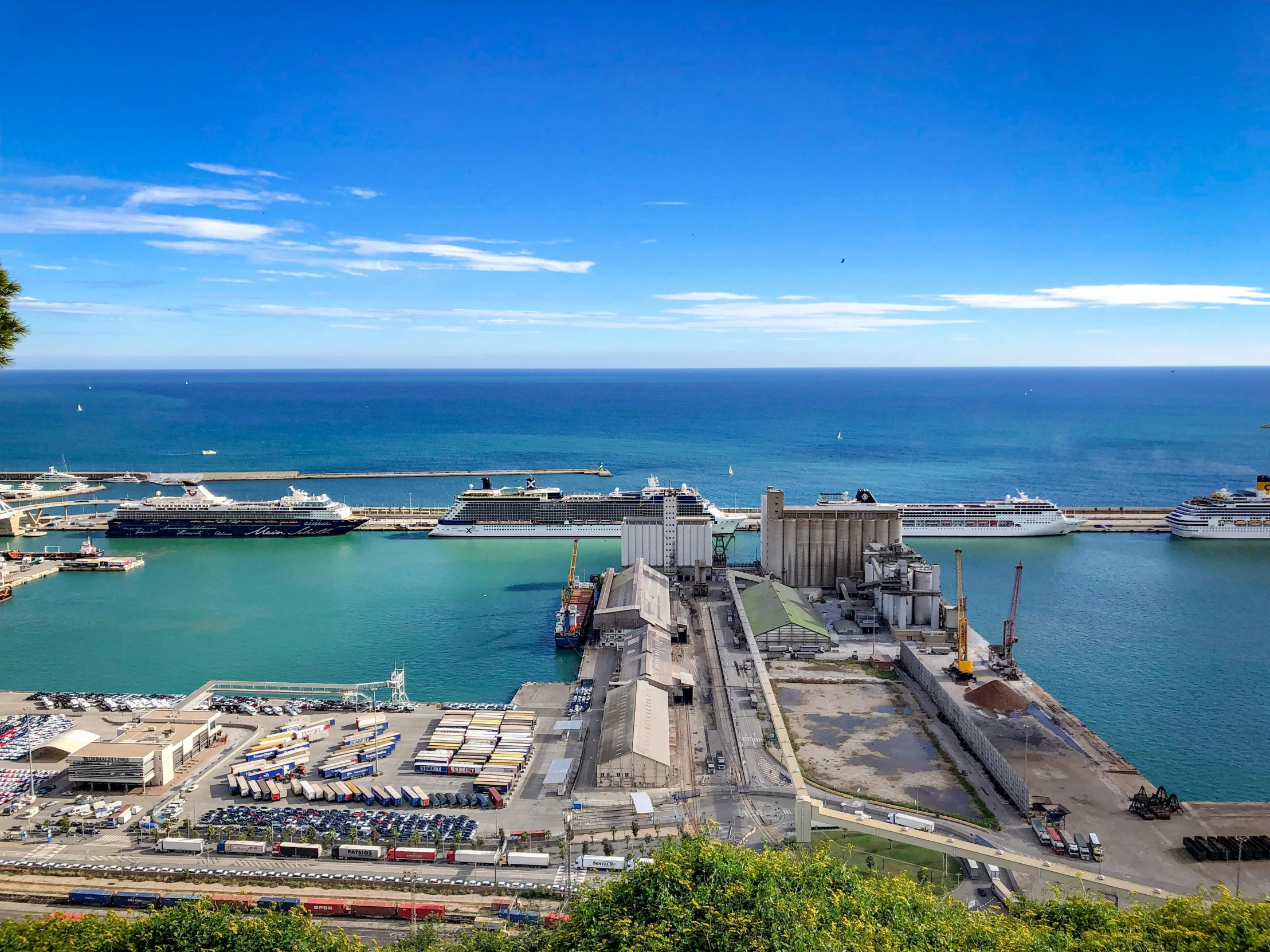 a large body of water sitting next to a lush green hillside, a tilt shift photo, pexels contest winner, figuration libre, shipping docks, in spain, navy, a photo of the ocean