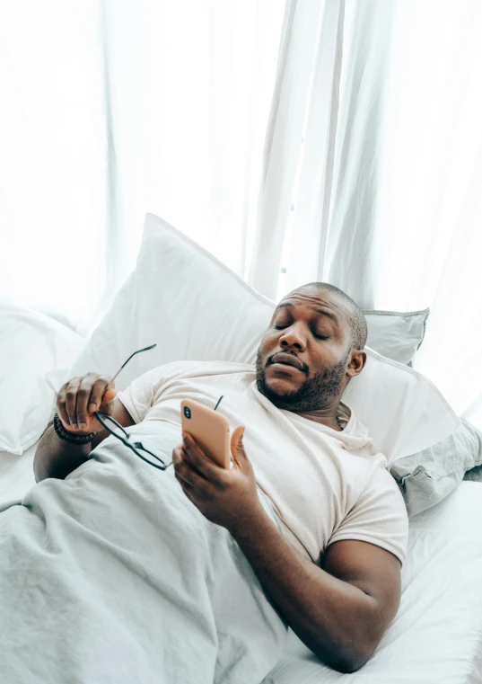 a man laying in bed reading a book, trending on pexels, happening, dave chappelle, looking at his phone, ray lewis, sickness