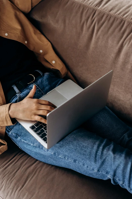 a woman sitting on a couch using a laptop, trending on pexels, renaissance, wearing jeans, medium close up, rounded lines, laying down