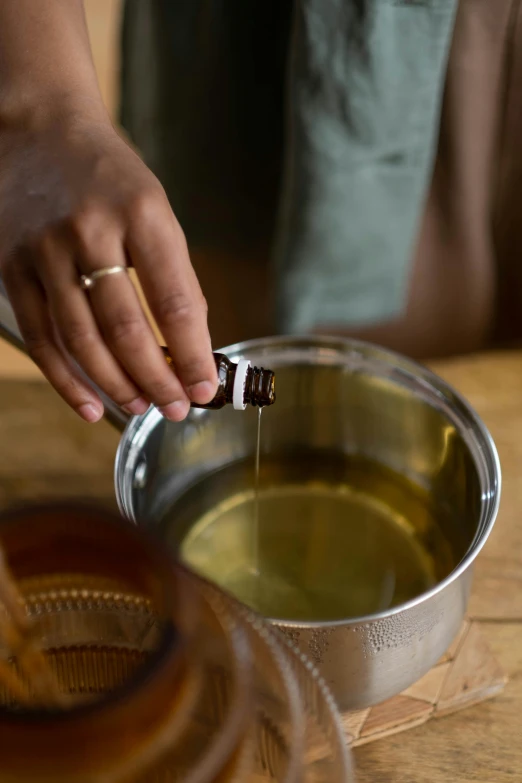 a person pours olive oil into a bowl, by Jessie Algie, incense, detailed product image, in liquid, stainless steel